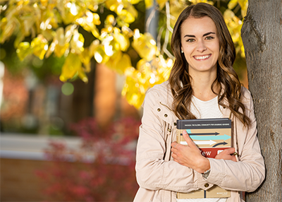 Student leaning against tree